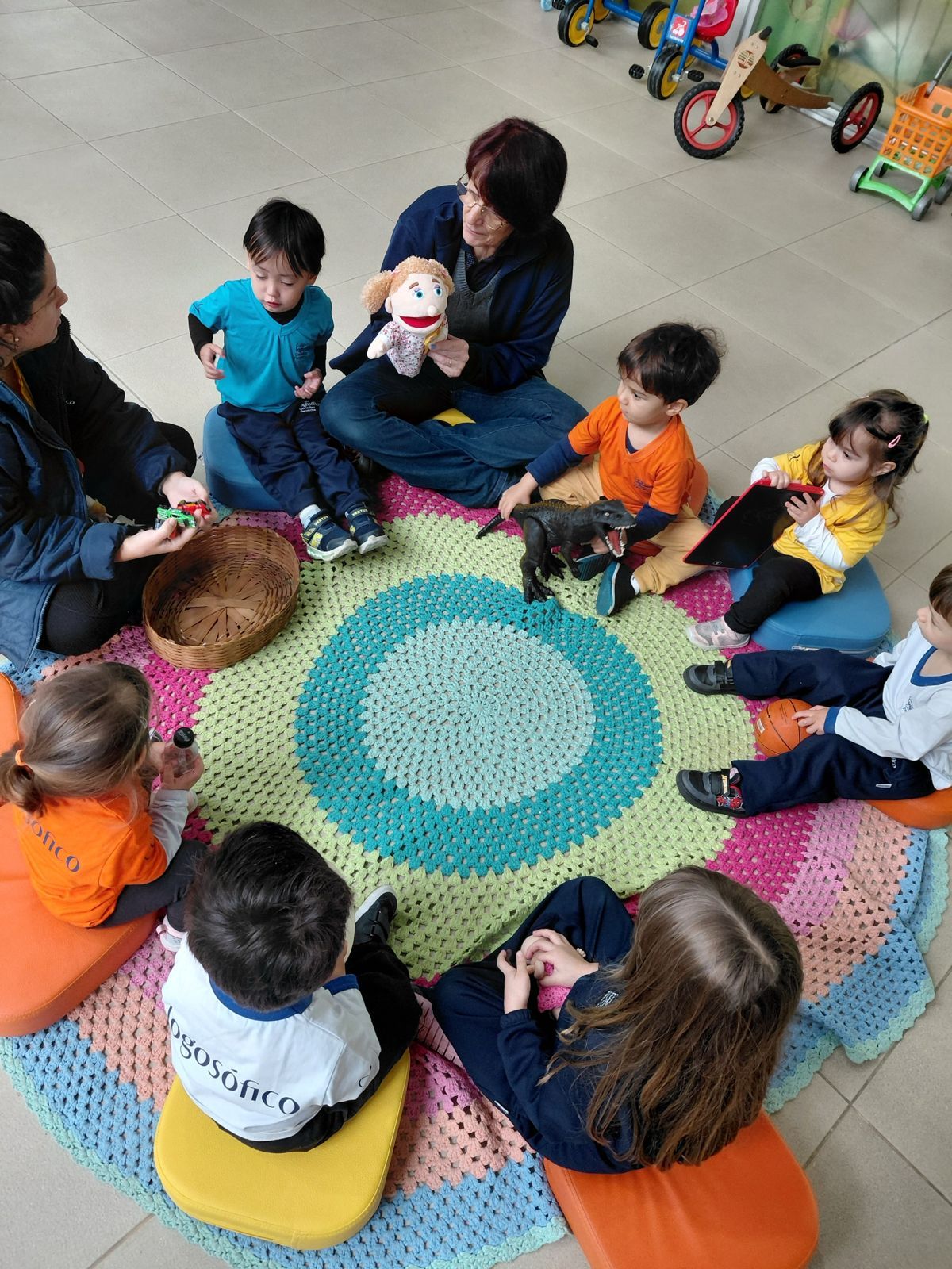 Roda de conversa com crianças e educadoras sobre um tapete de crochê